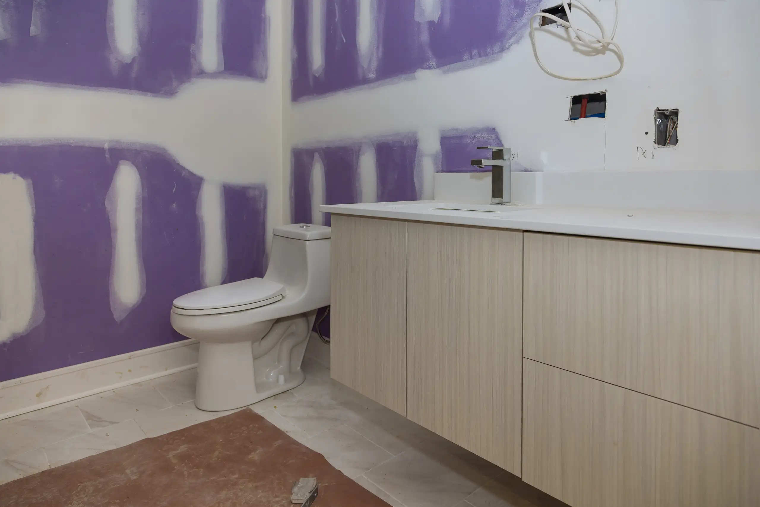 Badezimmer mit modernem Waschtisch und WC, teilweise renovierte Wände